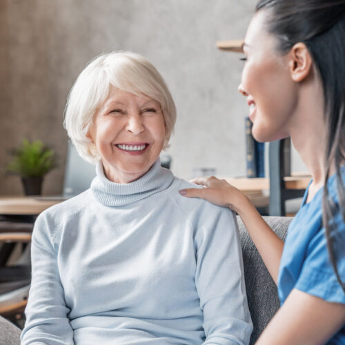 Vertical shot of helpful nurse taking care of senior woman in nursing home